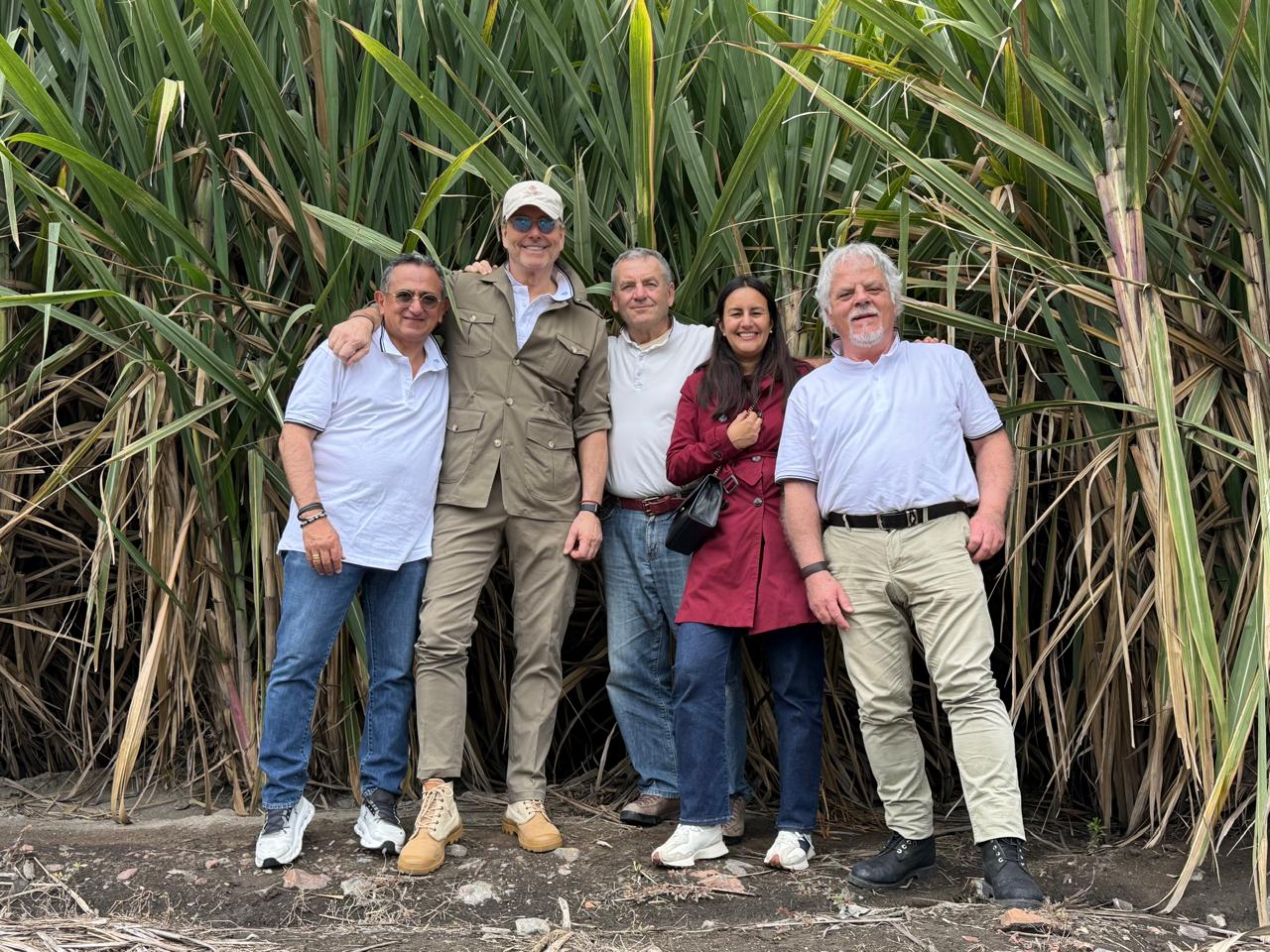 Gruppo di 4 componenti del team Nutrevo Quantic Evolution, azienda impegnata nella produzione sostenibile, insieme a una collega ecuadoriana davanti a una fitta piantagione di canna da zucchero in Ecuador.